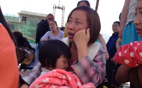 A woman weeps as she holds a young child in her arms in the earthquake-hit county of Luzhou, Sichuan Province on April 20. Photo: Simon Song